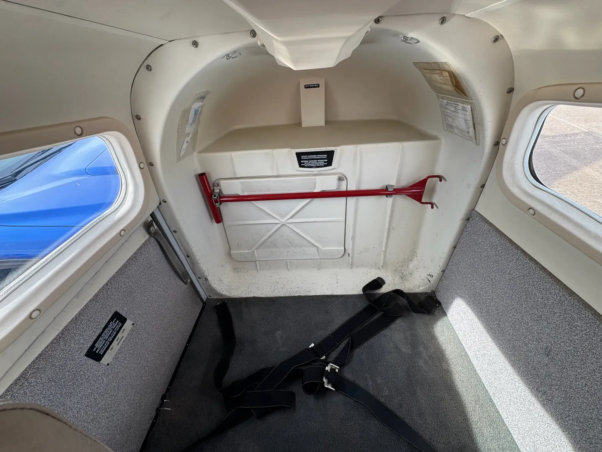 Baggage area behind the rear seats, with gray carpet and a cargo strap.