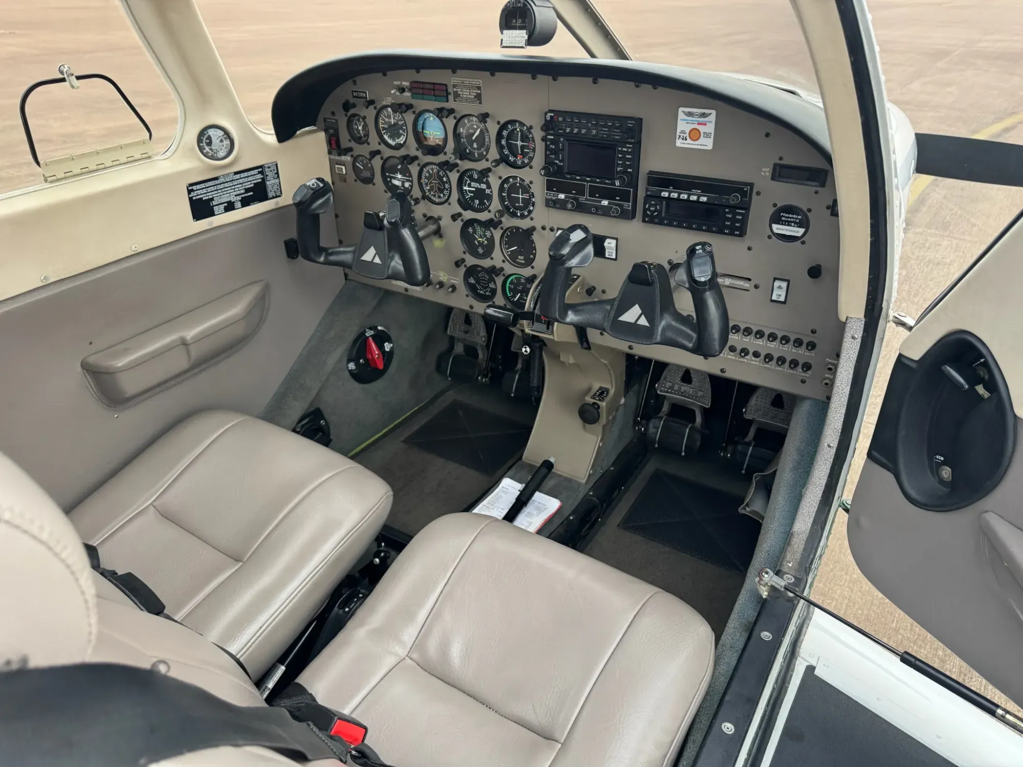 View through the open cabin door of the front seats and the instrument panel, with dual control yokes.