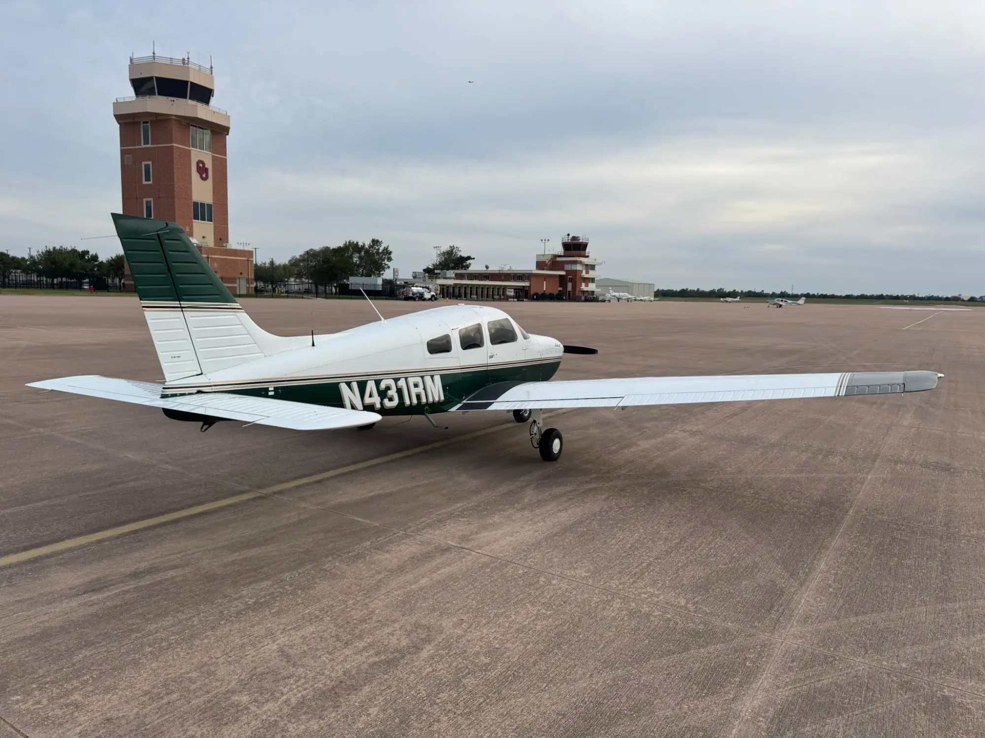 N431RM seen from the right rear quarter, with the green tail and the airport control tower behind it.